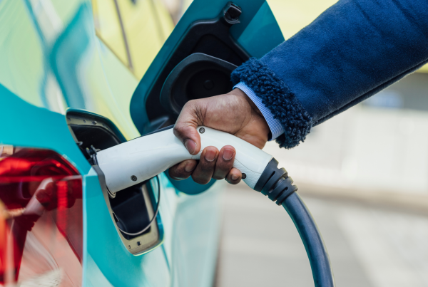 Electric vehicle being charged with connector in port, illustrating EV charger internal power supply and system stability.